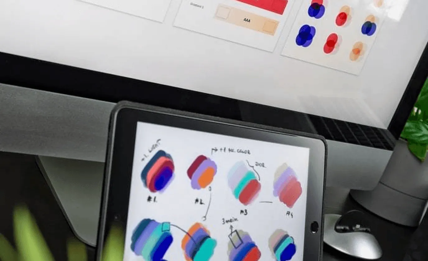 A tablet on a desk showing rows of colour swatches, from deep blue through violet to red.